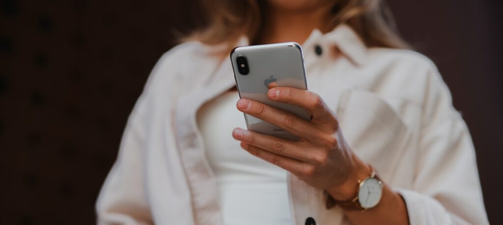 A person holds a silver smartphone