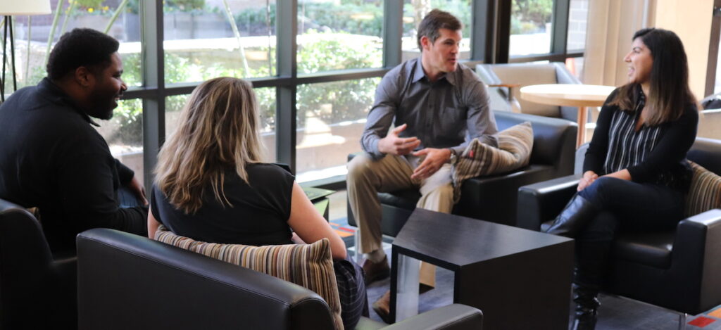 four consultants holding a discussion in an office setting