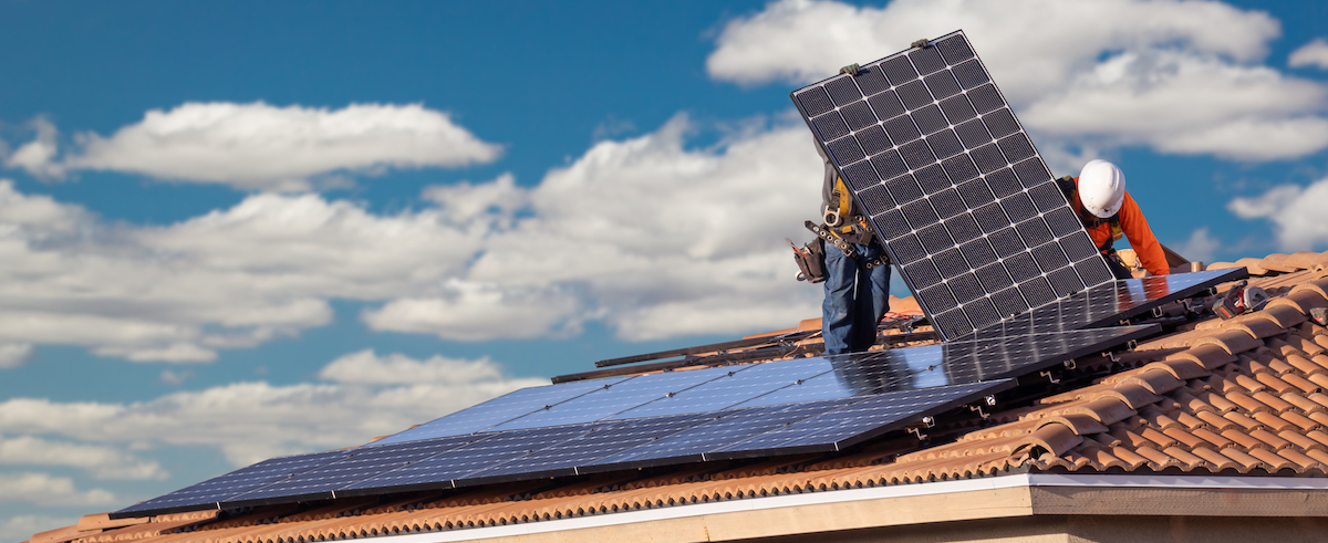 Workers Installing Solar Panels on House Roof