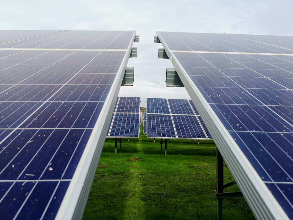 rows of photovoltaic solar panels against a green landscape and a clear sky