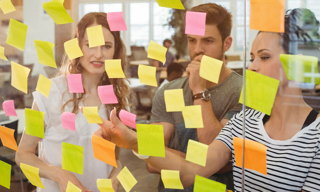team arranging sticky notes on a glass wall in an office setting