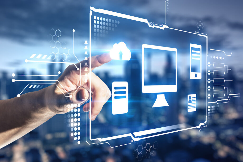 Hand touching a hologram desktop with different icons in it and city view in the background. Big data and technology concept