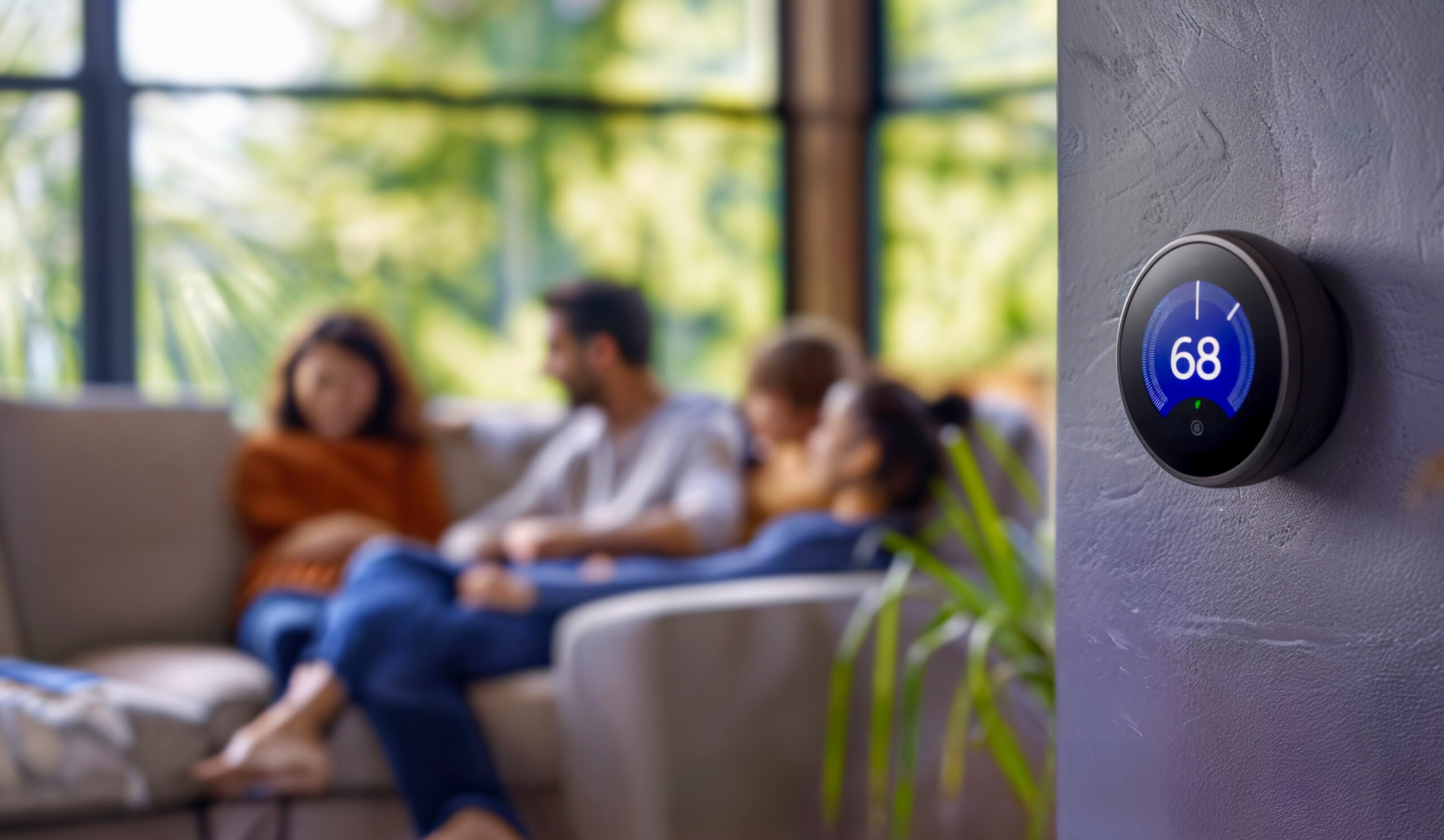 family relaxing at home with smart thermostat in the foreground