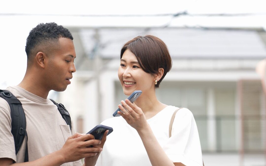 Asian woman showing her smartphone screen to an African American man