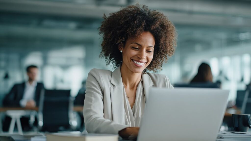 smiling woman working at a laptop computer in a modern office setting