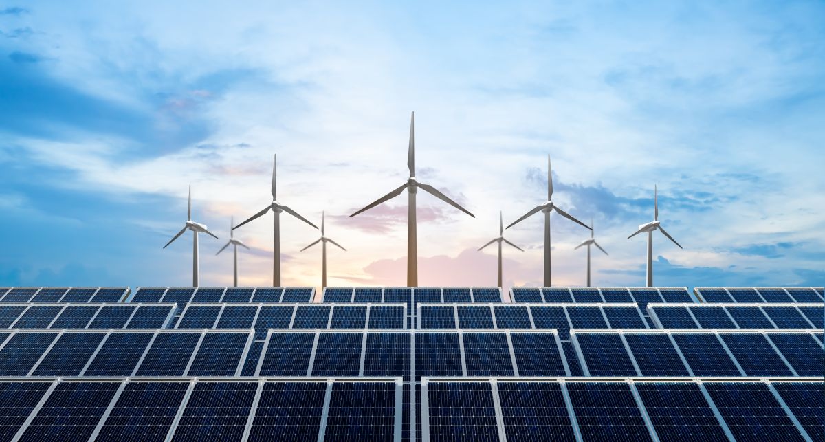 rows of solar panels in front of wind turbines against a sunny sky with wispy clouds