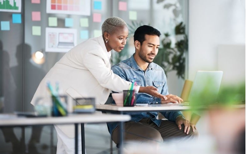woman and man collaborating around laptop PC in modern office setting