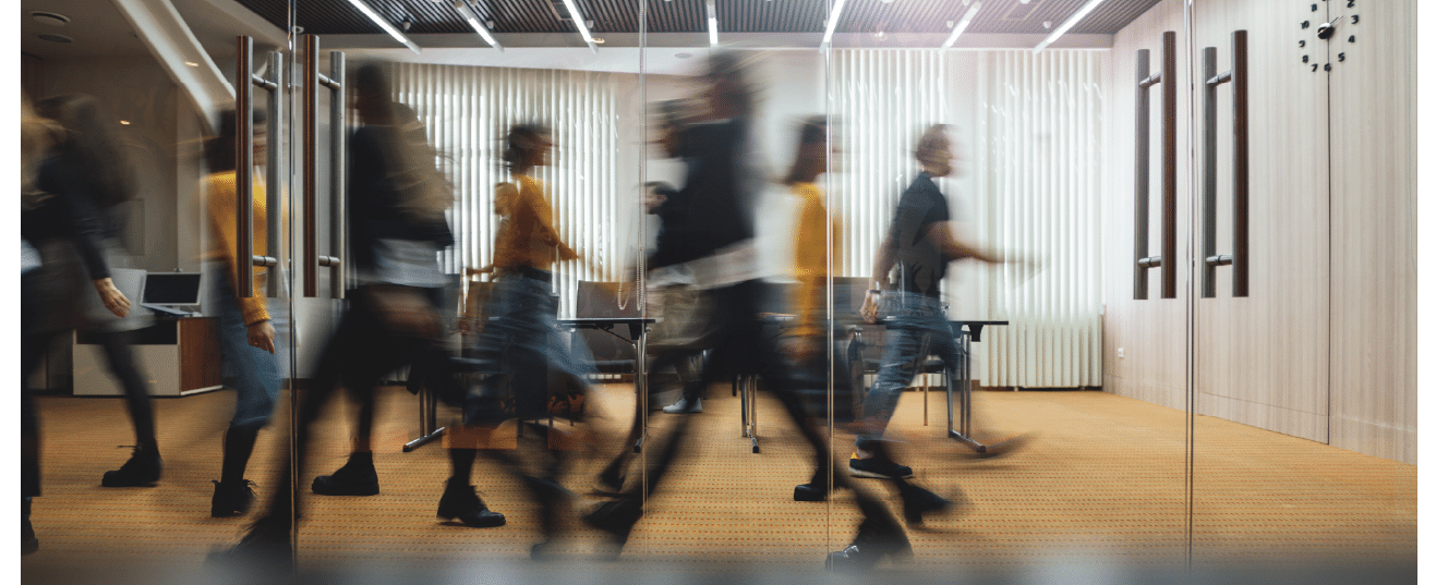 layered photo with blurred people walking across a boardroom