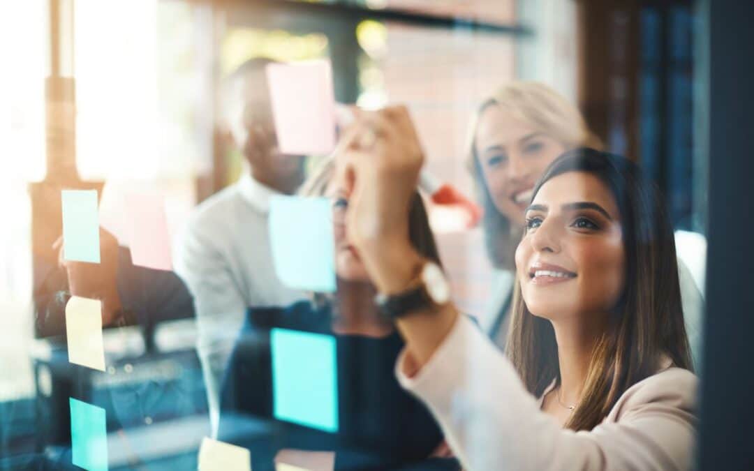 Team members collaborating during a planning workshop using sticky notes on a glass wall